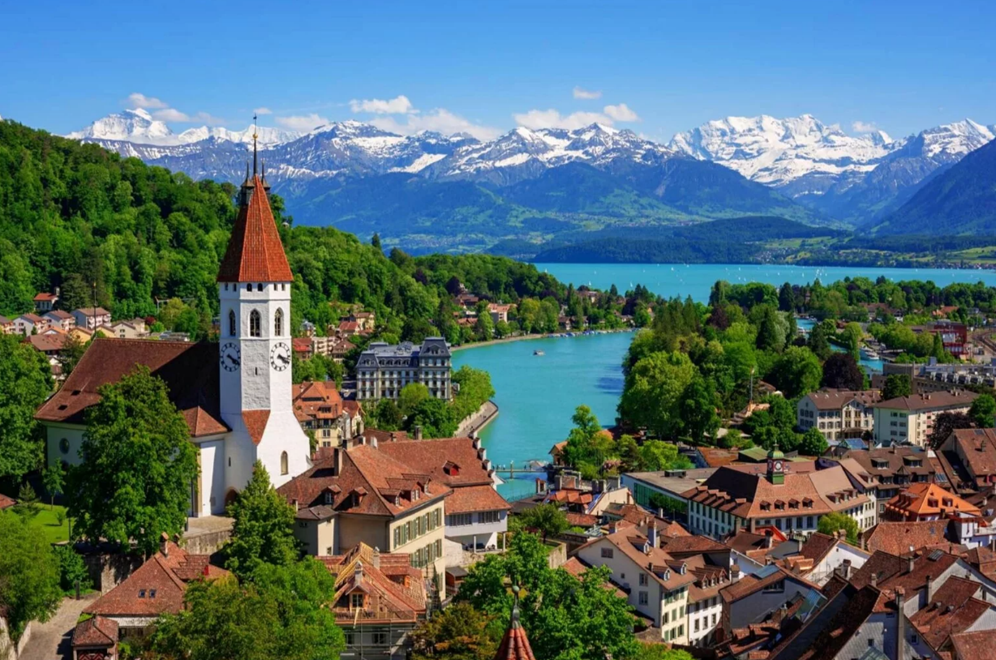 A city with a clock tower and a river and mountains in the background

AI-generated content may be incorrect.